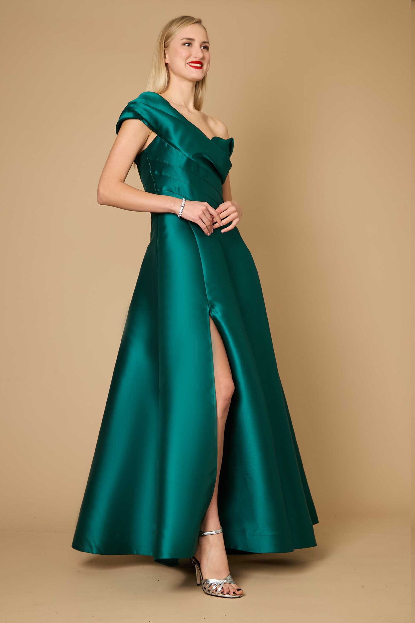 A stunning emerald green one-shoulder long formal ball gown, elegantly draping to the floor, perfect for evening events.