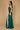 A stunning emerald green long fitted prom dress featuring an open back design, elegantly draping to the floor, perfect for a formal evening event.