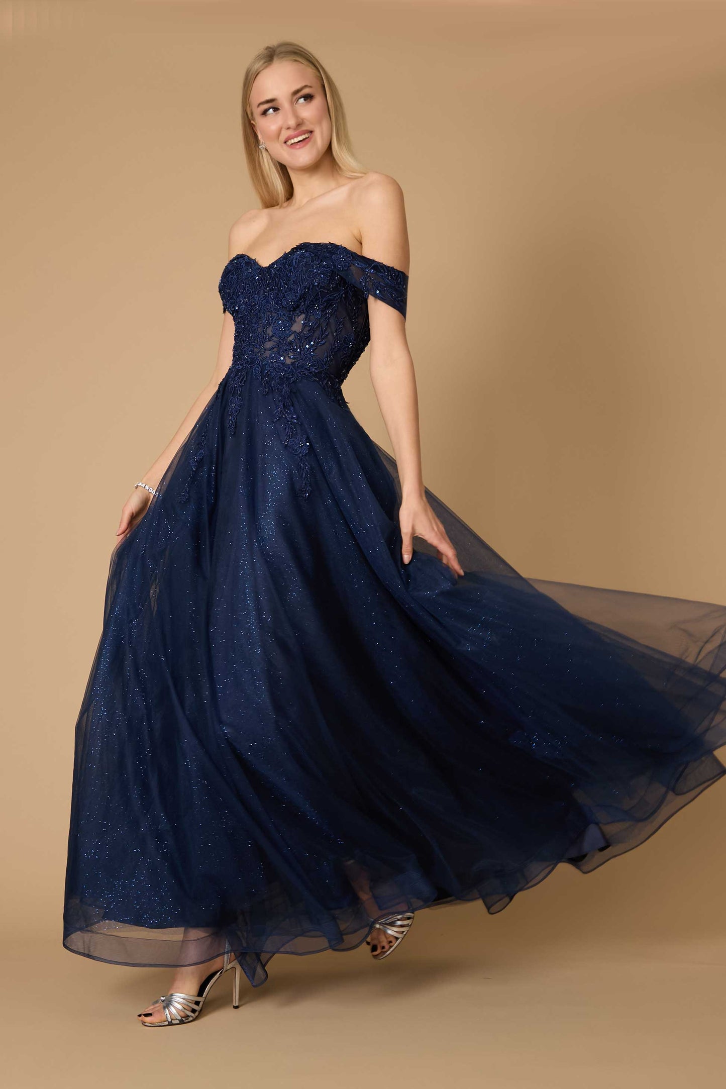 A model wearing a long off-shoulder navy corset formal dress, showcasing elegant draping and intricate detailing, set against a soft, neutral background.