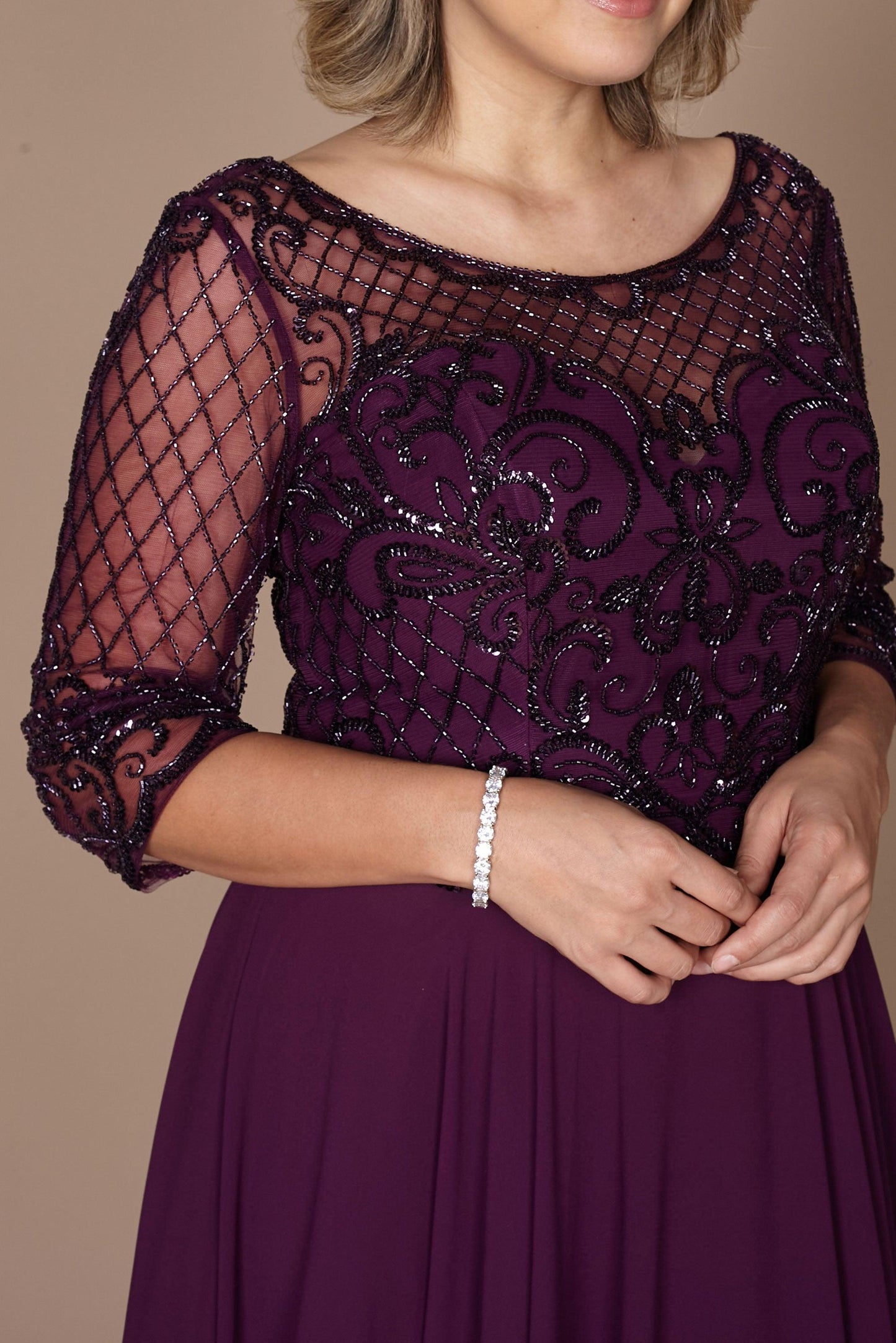 Elegant long sleeve mother of the bride dress in rich eggplant, adorned with intricate hand-beaded details, showcasing a sophisticated silhouette perfect for a formal wedding.